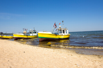 three yellow boats parked in the sea by the beach