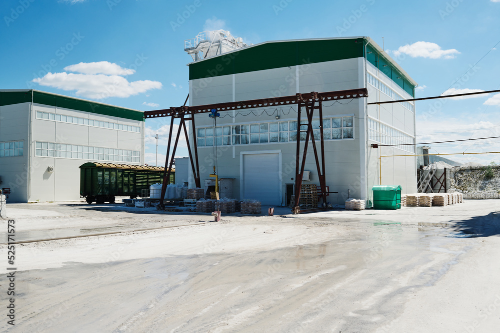 Wall mural two small white buildings of modern production factory standing in wide yard with blue sky and cloud