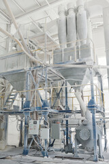 Part of huge metallic structure painted in white with control panel below standing inside spacious workshop of modern production factory