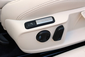Car seat adjustment. Buttons for adjusting seat position. Car interior detail. White leather interior of the luxury modern car.