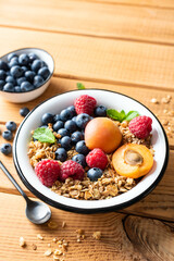 Granola bowl with berries and fruits on a wooden table background