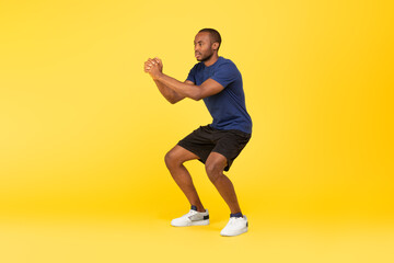 Fototapeta na wymiar Athletic African American Man Doing Deep Squat Exercise, Yellow Background
