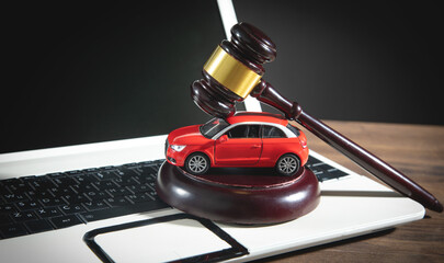 Judge gavel with a red toy car on the computer keyboard. Online car auction concept