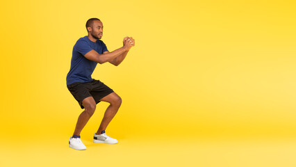 Fototapeta na wymiar Sporty Black Guy Exercising Doing Deep Squats Over Yellow Background