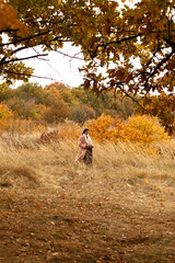 a woman in a pink coat walks in a beautiful autumn park