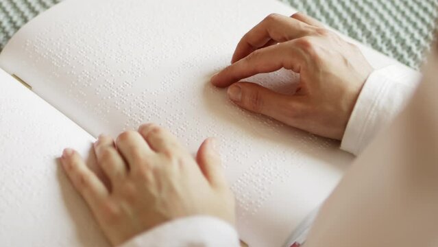 Poorly seeing woman learning Braille book. A person with blindness touches and reads with his hands.	