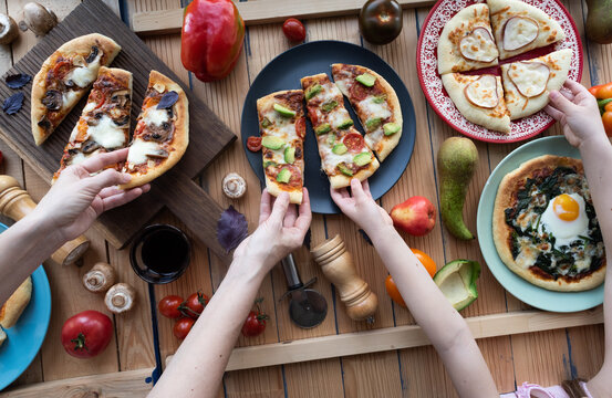 Different pizzas flat lay on shabby wooden box surface with tomato, basil and peppers overhead view