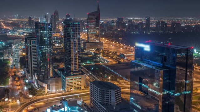 Aerial view of media city and al barsha heights district area during all night timelapse from Dubai marina. Towers and skyscrapers with lights turning off and traffic on a highway from above