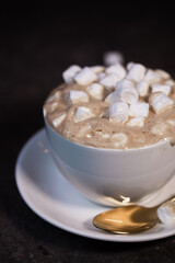 a white cup of coffee with marshmallows on the table