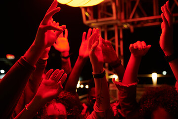Raised hands of young energetic friends dancing at rooftop party in outdoor cafe at night time and...