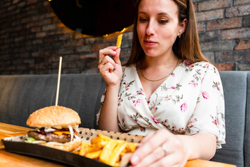 Burger eating woman. Pretty Young Happy Girl Eat Tasty Hamburger. Junk Food Concept.