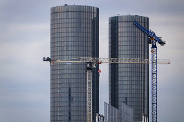 Obraz premium Large construction cranes and modern high-rise office buildings. Construction of new buildings in the city