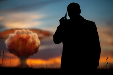 The concept of a nuclear strike. Silhouette of a man calling on the phone and giving the order to...