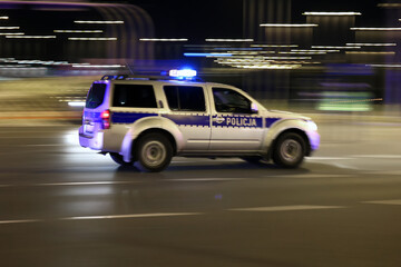 Radiowóz polskiej policji na sygnałach alarmowo szybko jedzie przez miasto na interwencję.  - obrazy, fototapety, plakaty