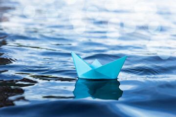origami paper sailboat sailing on blue water