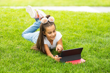 Naklejka na ściany i meble education, free time, technology and internet concept - little student girl with tablet pc