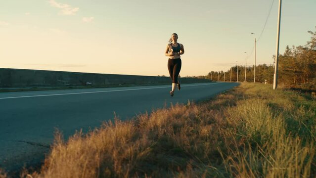 A girl in a sports top runs along the road.