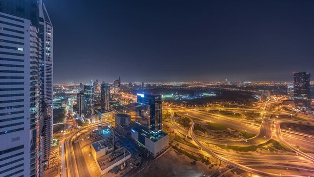 Aerial panoramic view of media city and al barsha heights district area during all night timelapse from Dubai marina with lights turning off. Towers and skyscrapers with traffic on a highway from