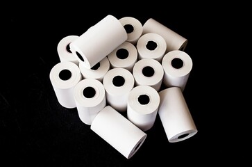 On a black background, white rolls of cash paper for the terminal and cash register equipment.  Background image, close-up, pattern.  Top view, flat lay.