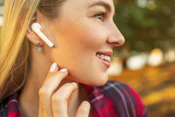 Close up of female ear with wireless earphone inside listening to music. Young beautiful woman with wireless earphones on her ears.