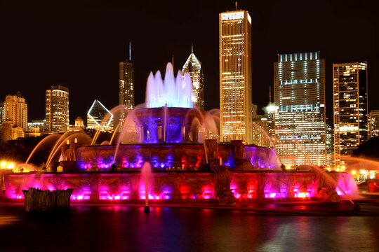 CHICAGO -  Buckingham Fountain illuminated at night against the backdrop of downtown skyscrapers