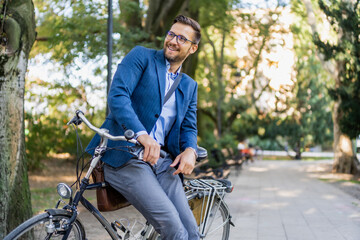 Obraz premium A young smiling, stylish men posing leaned on his bicycle.
