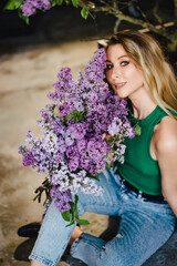 a blonde woman in a green top and jeans with lilac flowers. 