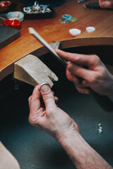 Delicate jewelry work. Close up of a male jeweler working and shaping an unfinished ring with a tool in workshop