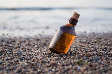 Essential oil bottle on a beach with rocks. Little brown medicine bottle in nature background....