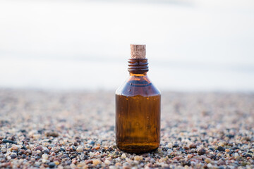 Essential oil bottle on a beach with rocks. Little brown medicine bottle in nature background. Organic CBD hemp oil.