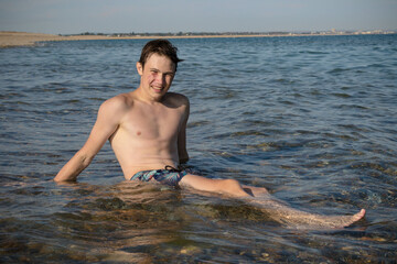 A 17 Year Old Teenage Boy Sitting On A Beach