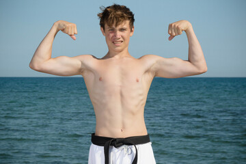 A Shirtless 17 Year Old Teenage Boy Flexing His Muscles