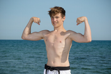 A Shirtless 17 Year Old Teenage Boy Flexing His Muscles