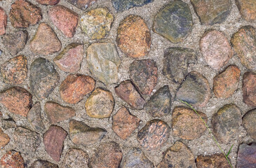 Natural stone wall background texture, showing a clearly brick-built natural stone wall with different size stones in brown and gray color. The stone wall constructed by gray wall