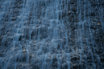 Waterfall texture. Background of the falling purest mountain water. A cascade of blurred motion. Natural abstract background for design. The concept of life, ecology, environmental protection.