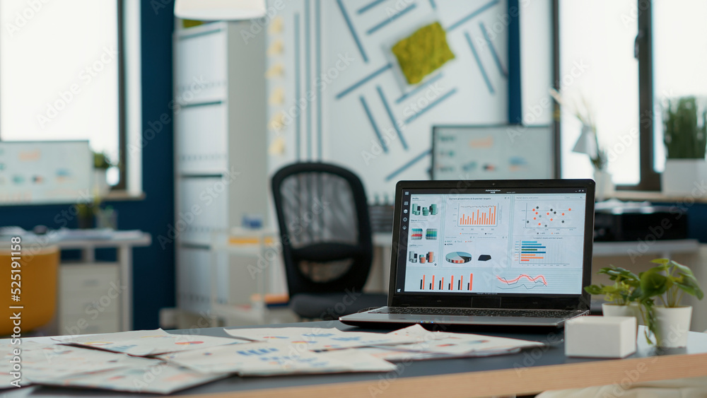 Wall mural empty startup office with laptop showing business mangement software on display showing moving chart