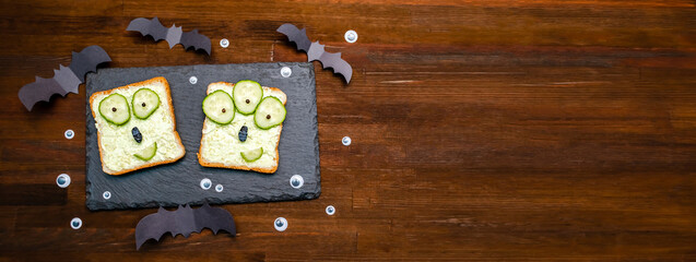 Funny monster faces on halloween sandwich toast bread with soft green avocado cheese ricotta...