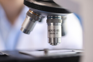 Scientist analyzing microscope slide at laboratory. Young woman technician is examining a histological sample, a biopsy in the laboratory of cancer research