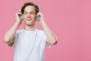 Obraz na płótnie Canvas a teenager listens to music on headphones, closing his eyes in pleasure and holding his hands on the headphones