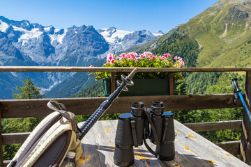 backpack with trekking poles and binoculars to enjoy panoramic view to Ortles Mountain range from Furkelh&uuml;tte, Trafoi, Italy; alpine healthy lifestyle concept