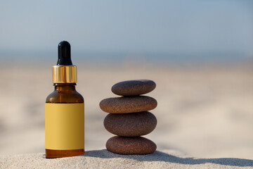 Mock-up for a medicinal, natural product. Zen stones and a dropper amber bottle on the sand of a...