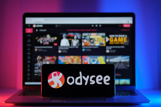 ODYSEE video platform logo seen on screen of smartphone and actual website seen on blurred laptop screen. New media platfom. Stafford, United Kingdom, August 22, 2022
