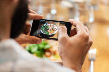 technology and people concept - close up of man with smartphone photographing food at restaurant