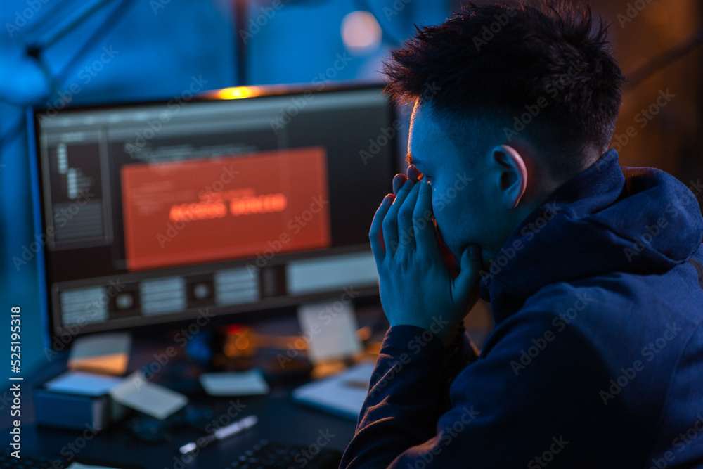 Poster cybercrime, hacking and technology concept - close up of male hacker in dark room using computer vir