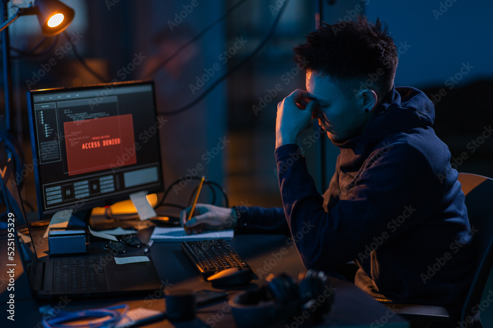 Poster cybercrime, hacking and technology concept - male hacker in dark room writing to notebook and using 