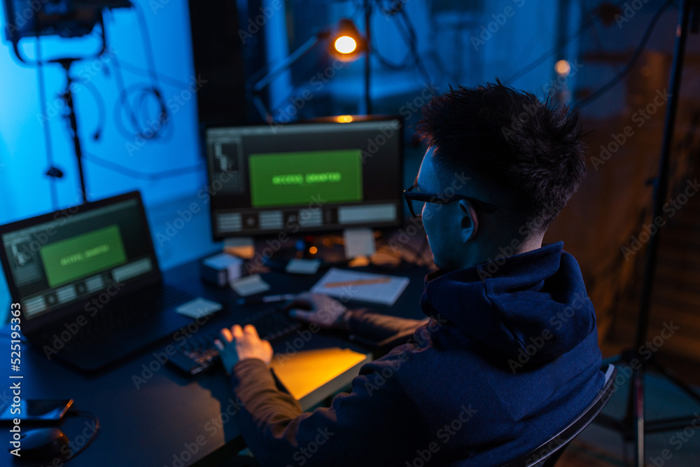 Poster cybercrime, hacking and technology concept - male hacker in dark room writing code or using computer