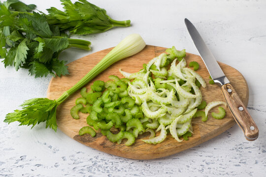 Wooden board with chopped stalk celery on a light blue background, top view. The concept of cooking delicious homemade vegan food.