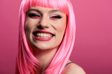 Portrait of sexy woman showing candid perfect smile on camera, feeling happy and positive. Model smiling and having white teeth, wearing beautiful makeup and pink hair wig to feel pretty.