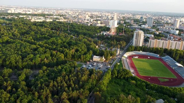 Drone view of Kharkiv city center near Park of Maxim Gorky, stadium and residential multistory buildings with scenic sunset light in summer