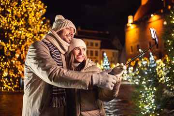 winter holidays and people concept - happy smiling couple taking picture with smartphone on selfie...